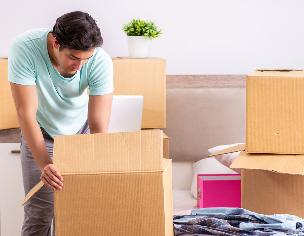 Family quickly packing moving boxes during a last-minute move with emergency packing hacks and supplies scattered around the room
